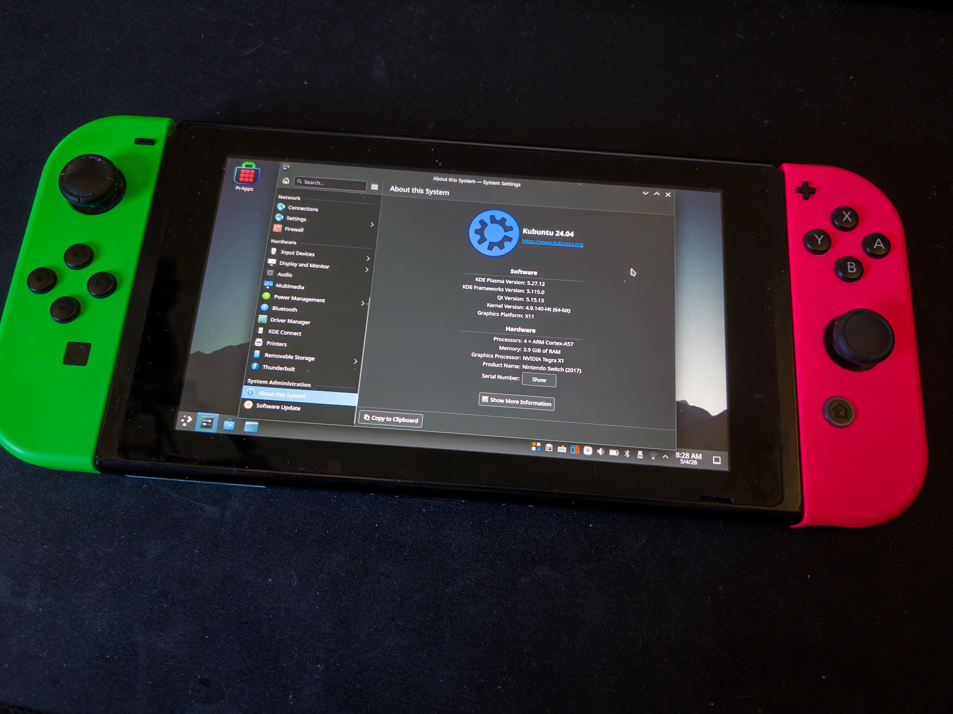 A Nintendo Switch tablet with connected green and pink Joy-Con controllers (left and right respectively). The screen shows a KDE Plasma desktop. An open window shows that the system is running Kubuntu 24.04.